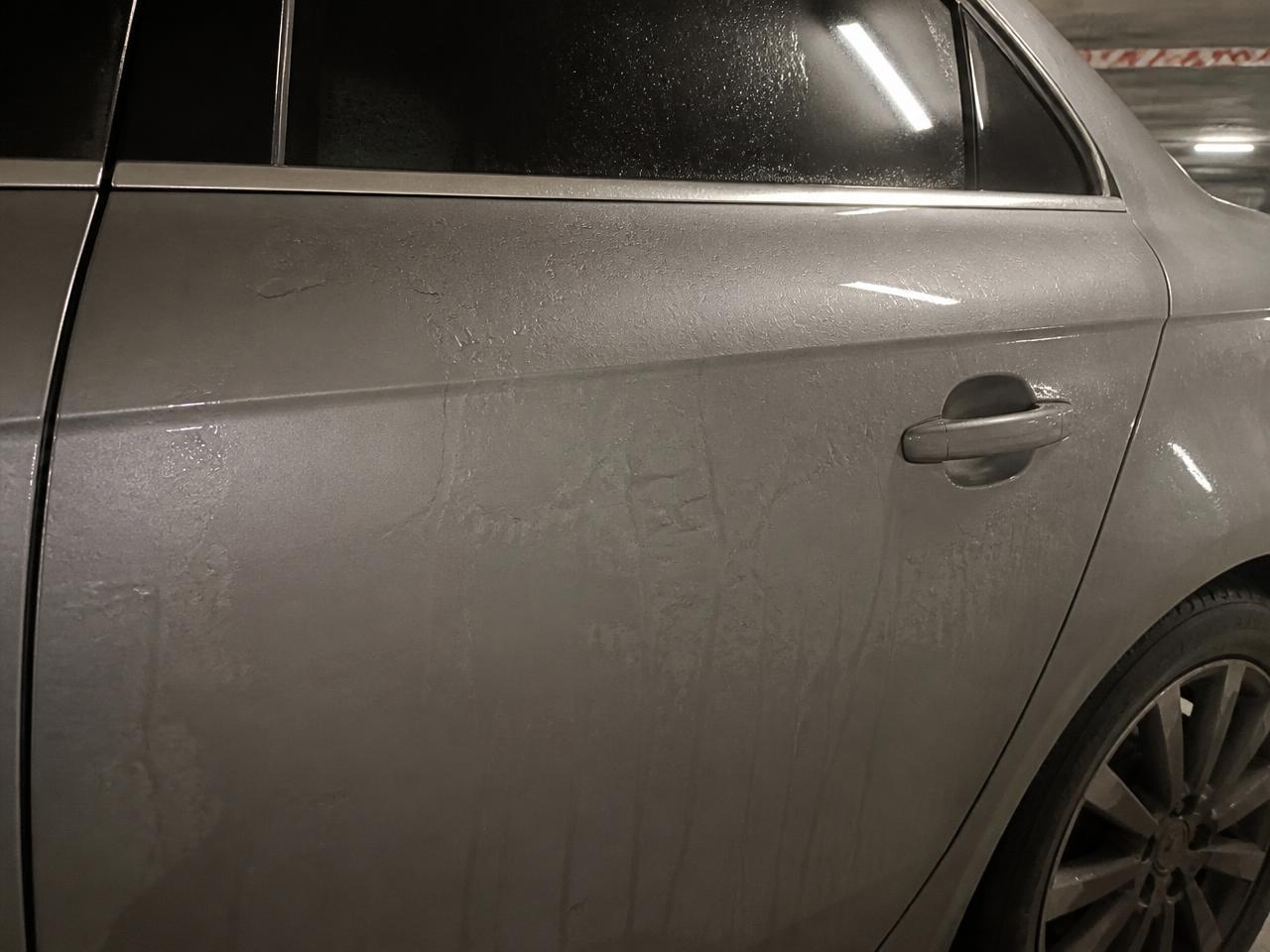 Wet grey car door before ceramic coating: water spreads in flat sheets across the paint