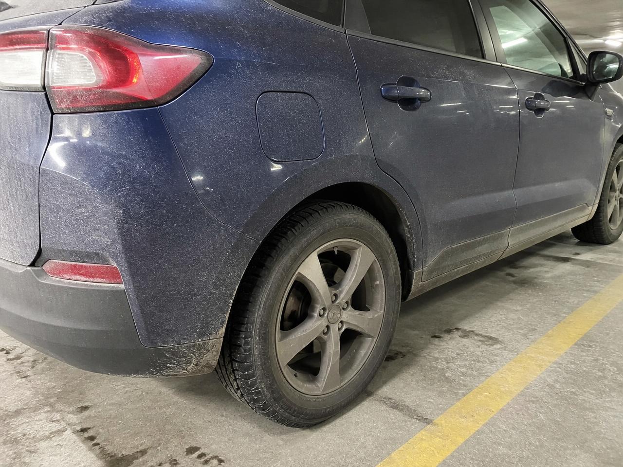 Rear quarter panel and wheel of an SUV before washing, covered in road salt film and brake dust