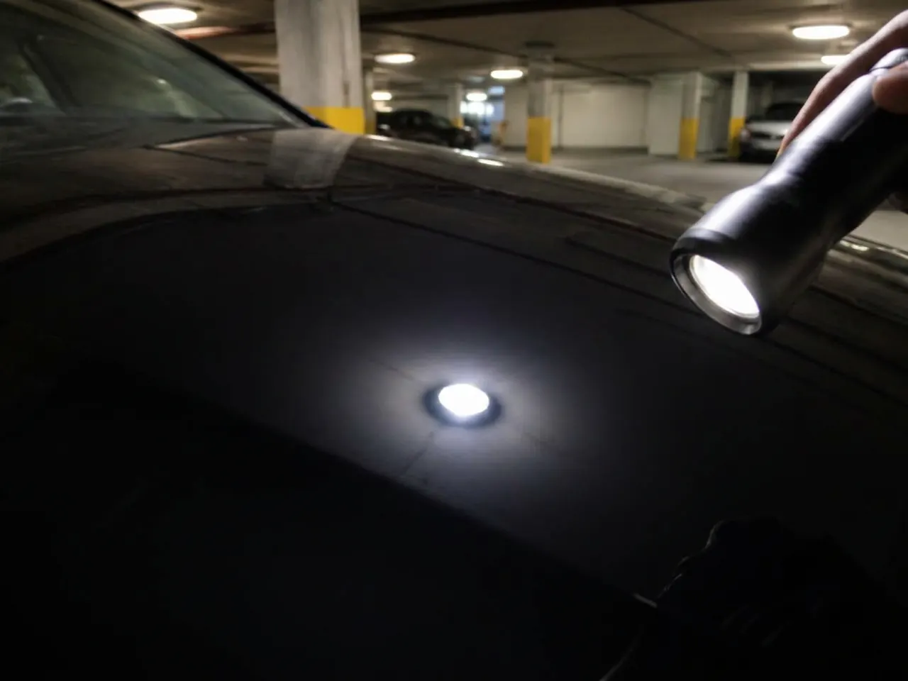 Same black hood after paint correction: crisp reflection, no swirl marks